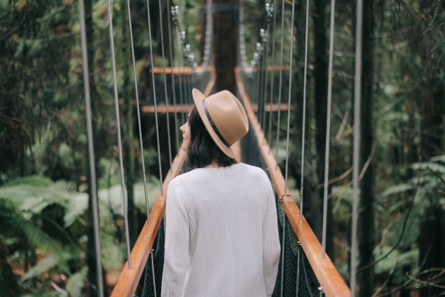 girl walking along a bridge surrounded in forest.