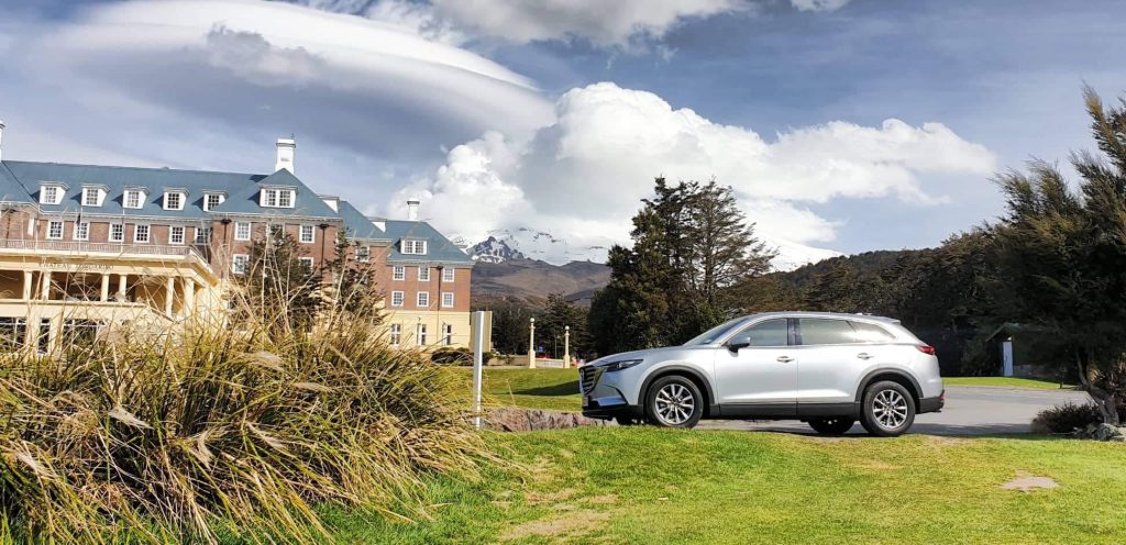 Mazda cx9 parked outside chateau tongariro with mount ruapehu in background.