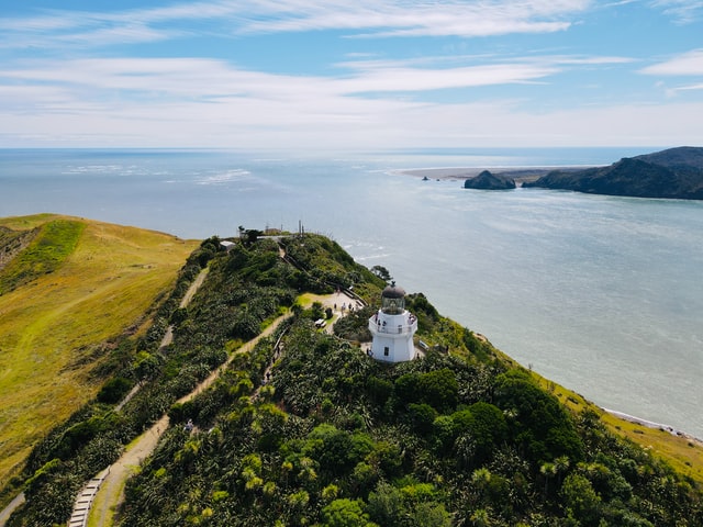 Manukau heads lighthouse on a hill with sea in background 