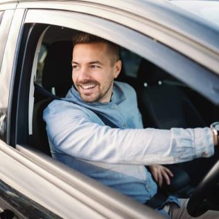 smiling man looking out window of car