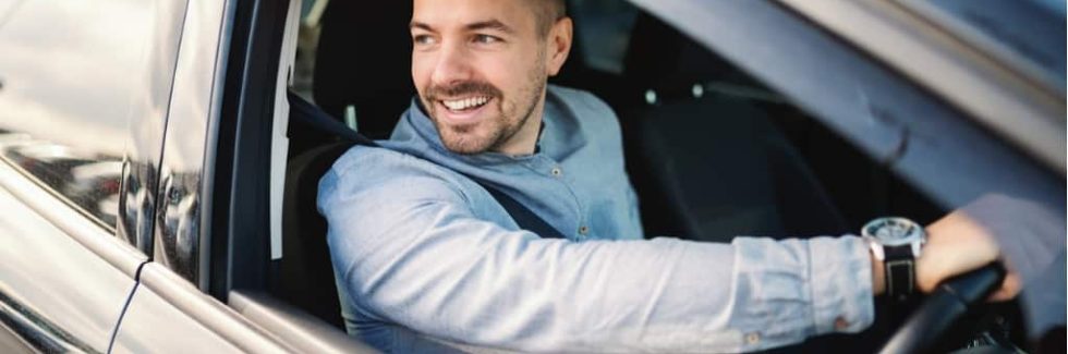 smiling man looking out window of car