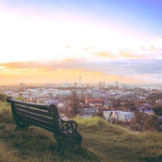 seat on a mountain with auckland city in background