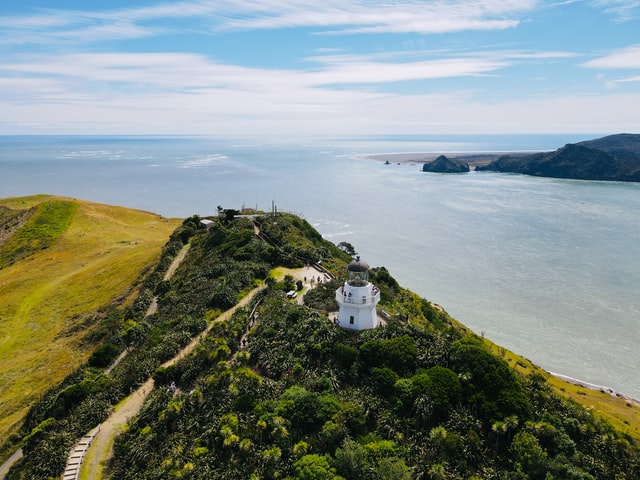 manukau heads lighthouse at the end of green penninula with sea in background