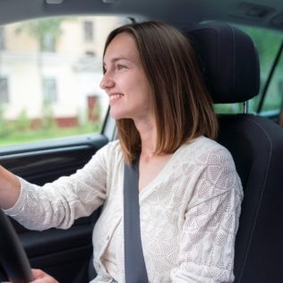 woman driving car with baby in back