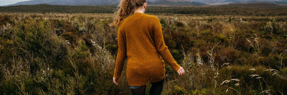 woman walking across a grass field